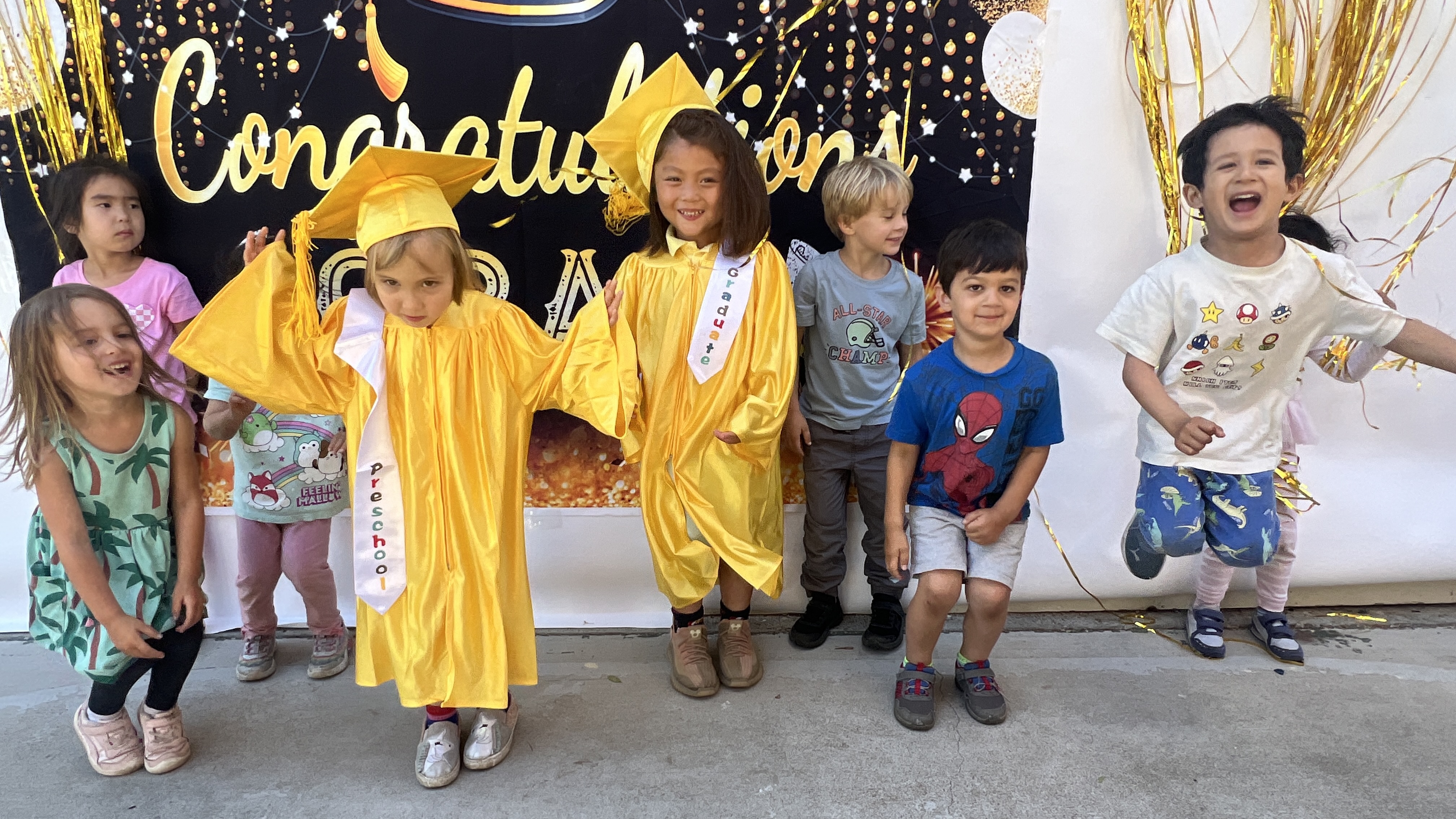Apple Land Kids graduation day - Pre-K children in golden caps and gowns with families in Santa Clara CA